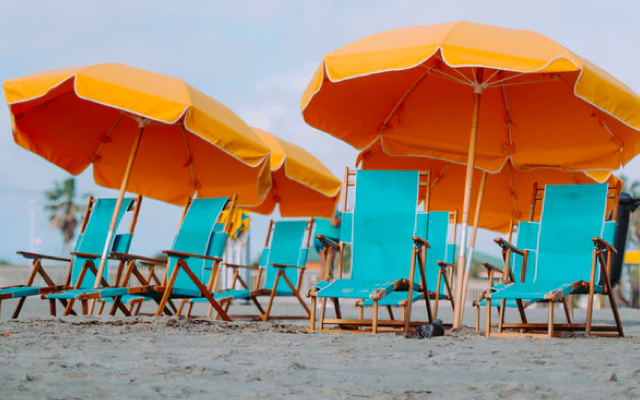 Orange umbrellas and blue beach chairs lined up on a sandy beach